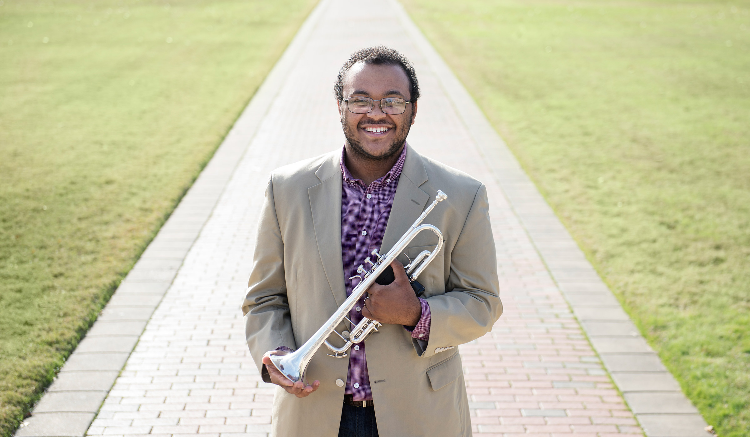 Photo of Quinlan Gray standing on the Drill Field with his trumpet