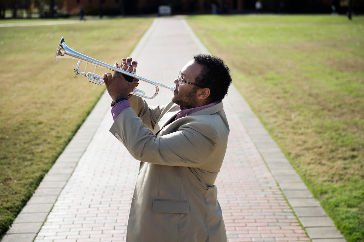 Music Education Major Quin Gray standing on the Drill Field at MSU holding a trumpet about to play.
