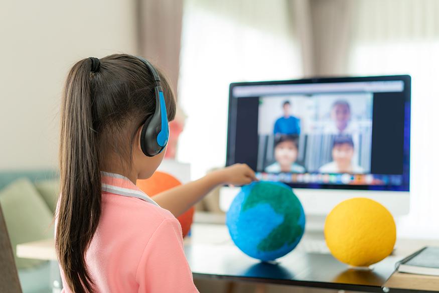 Photo of child with models of the planets in a classroom setting.