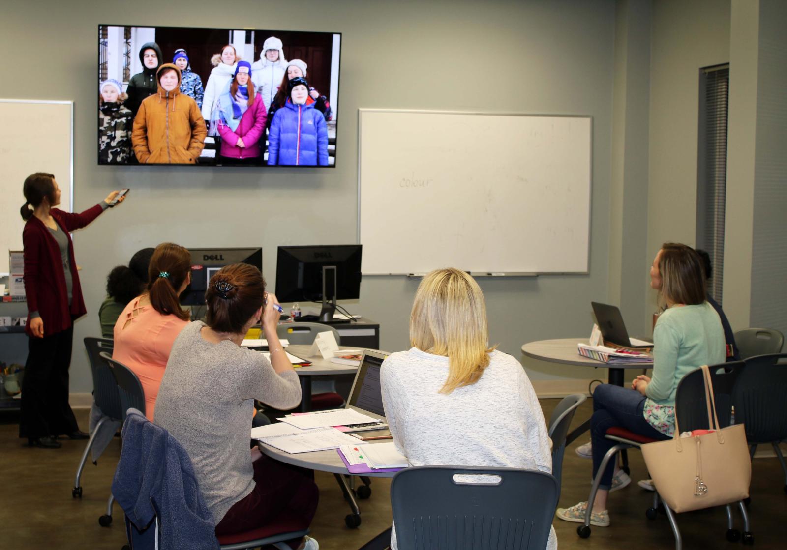 Photo of teacher and students in the classroom looking up at a tv.