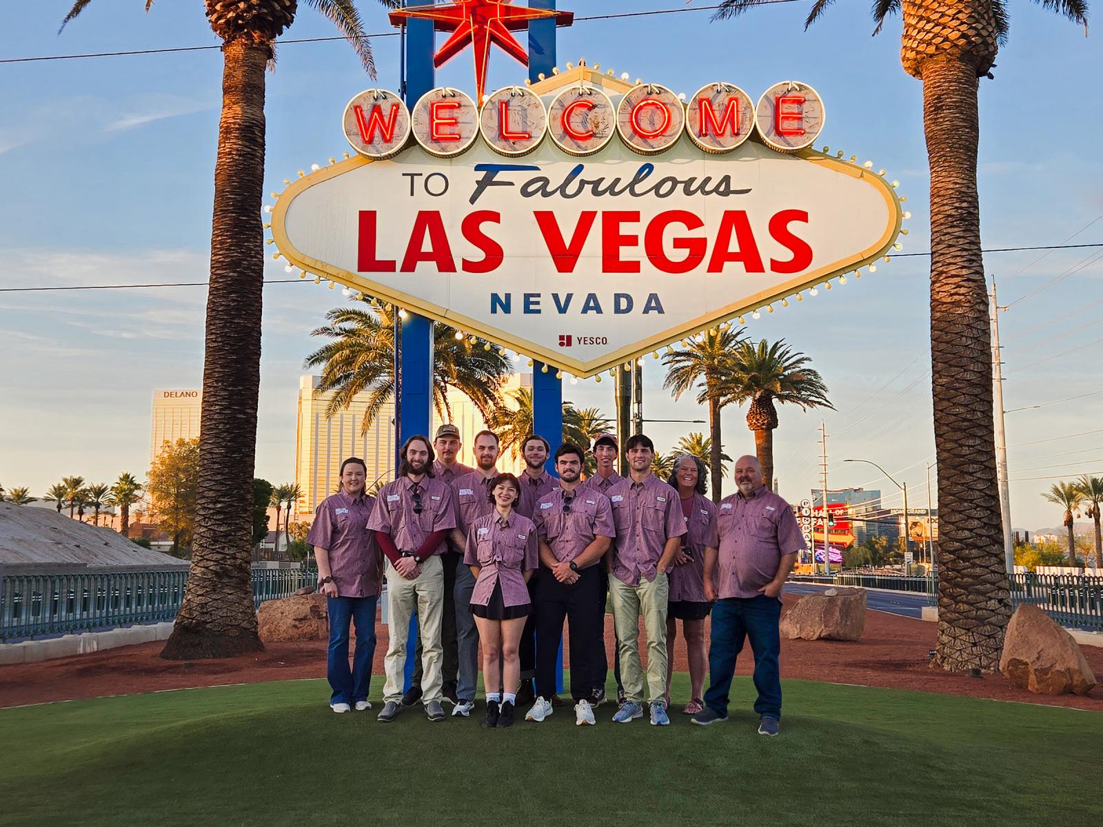Faculty and students pose for a picture under the Las Vegas sign