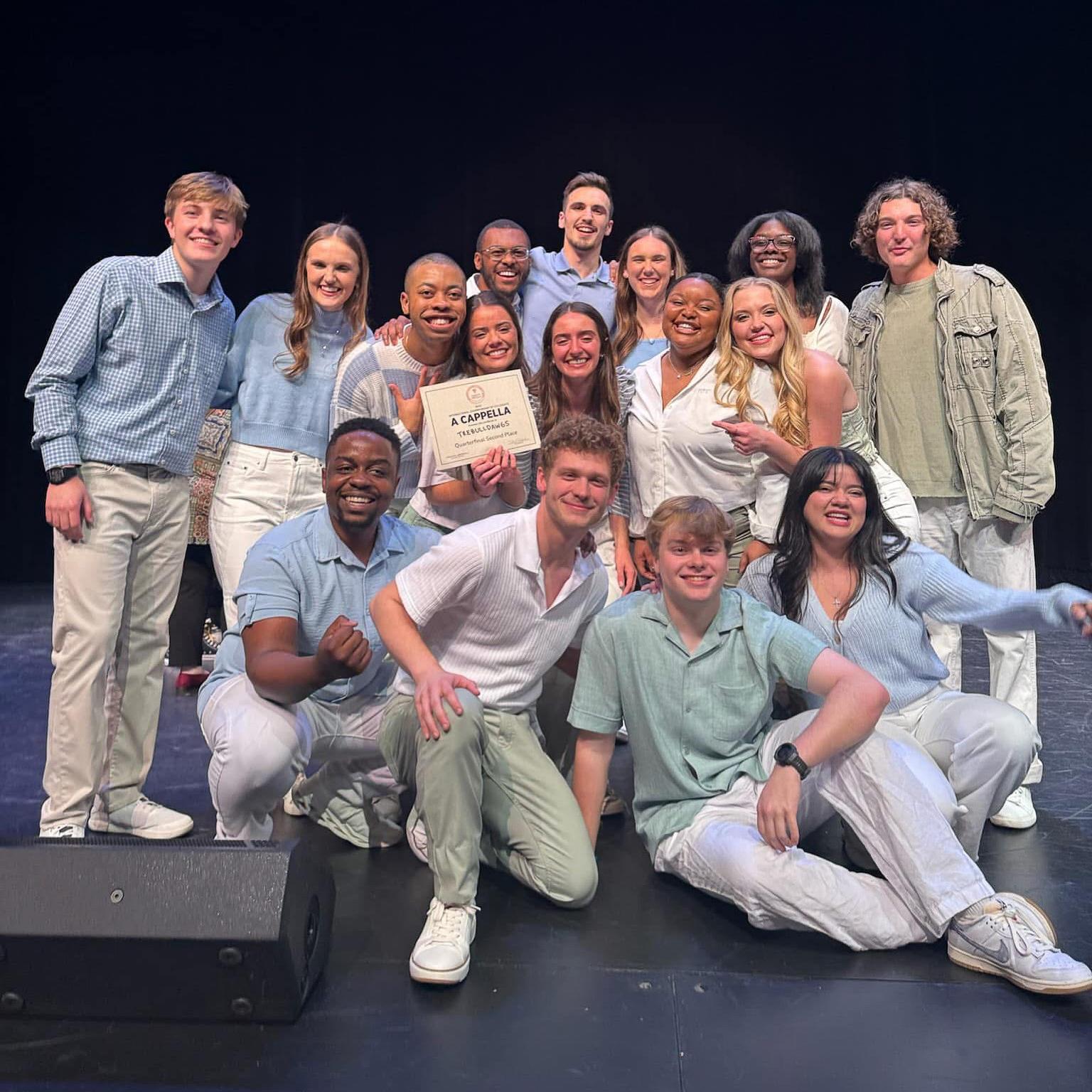 Trebulldawgs pose for a group photo on a stage