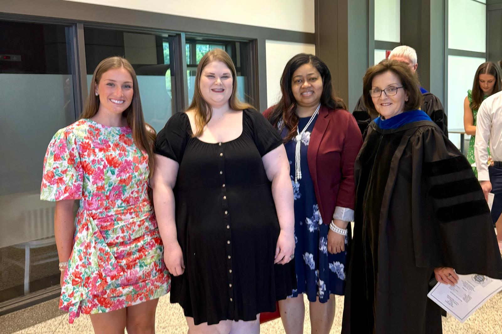Three College of Education students pose for a photo with Dean Jayroe.