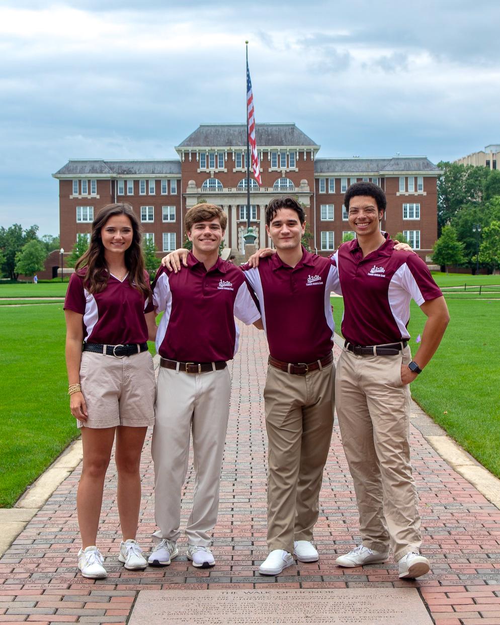 Four drum majors pose for a photo on the Drill Field