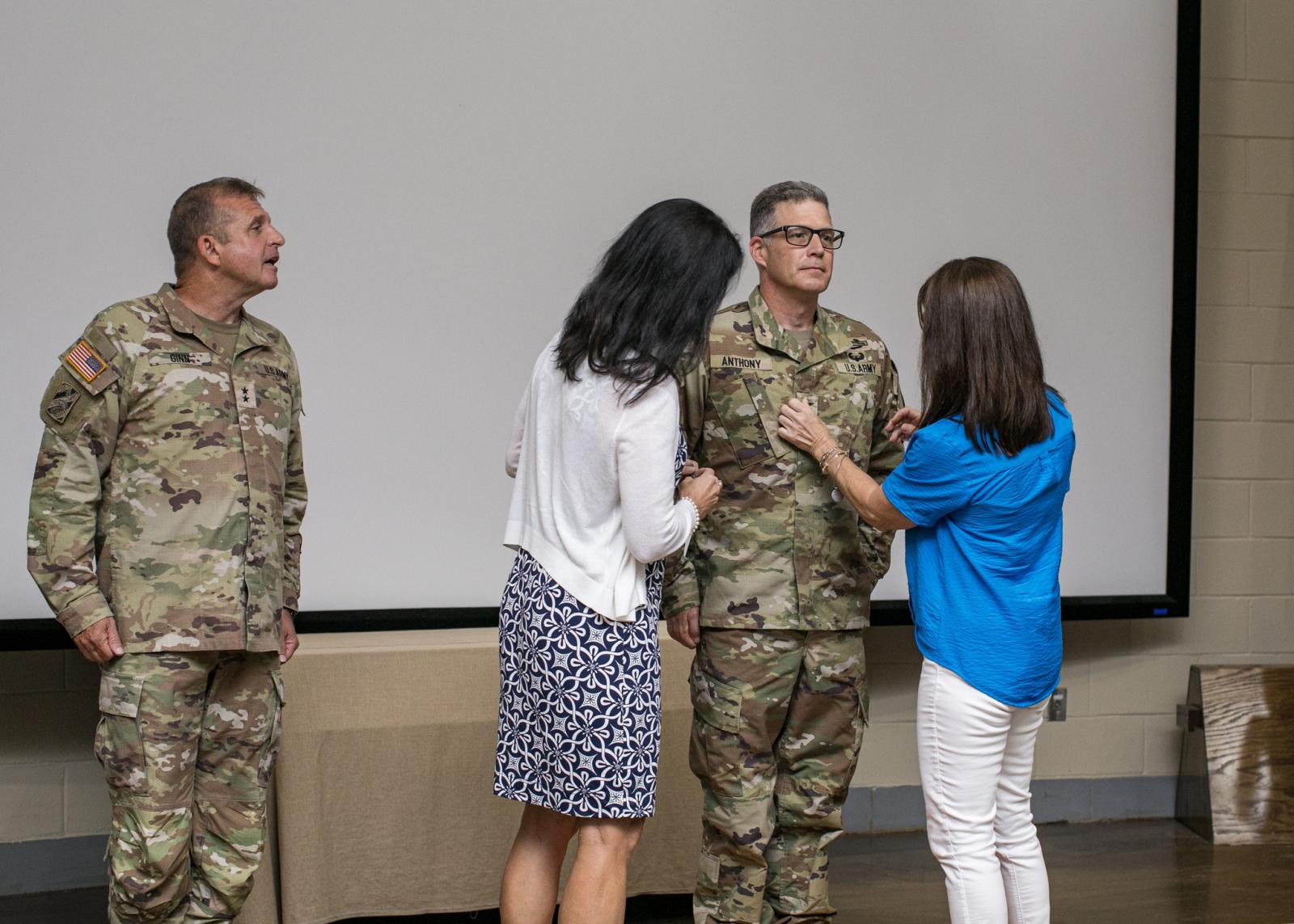 Anthony's sisters pin his new rank on his military uniform.