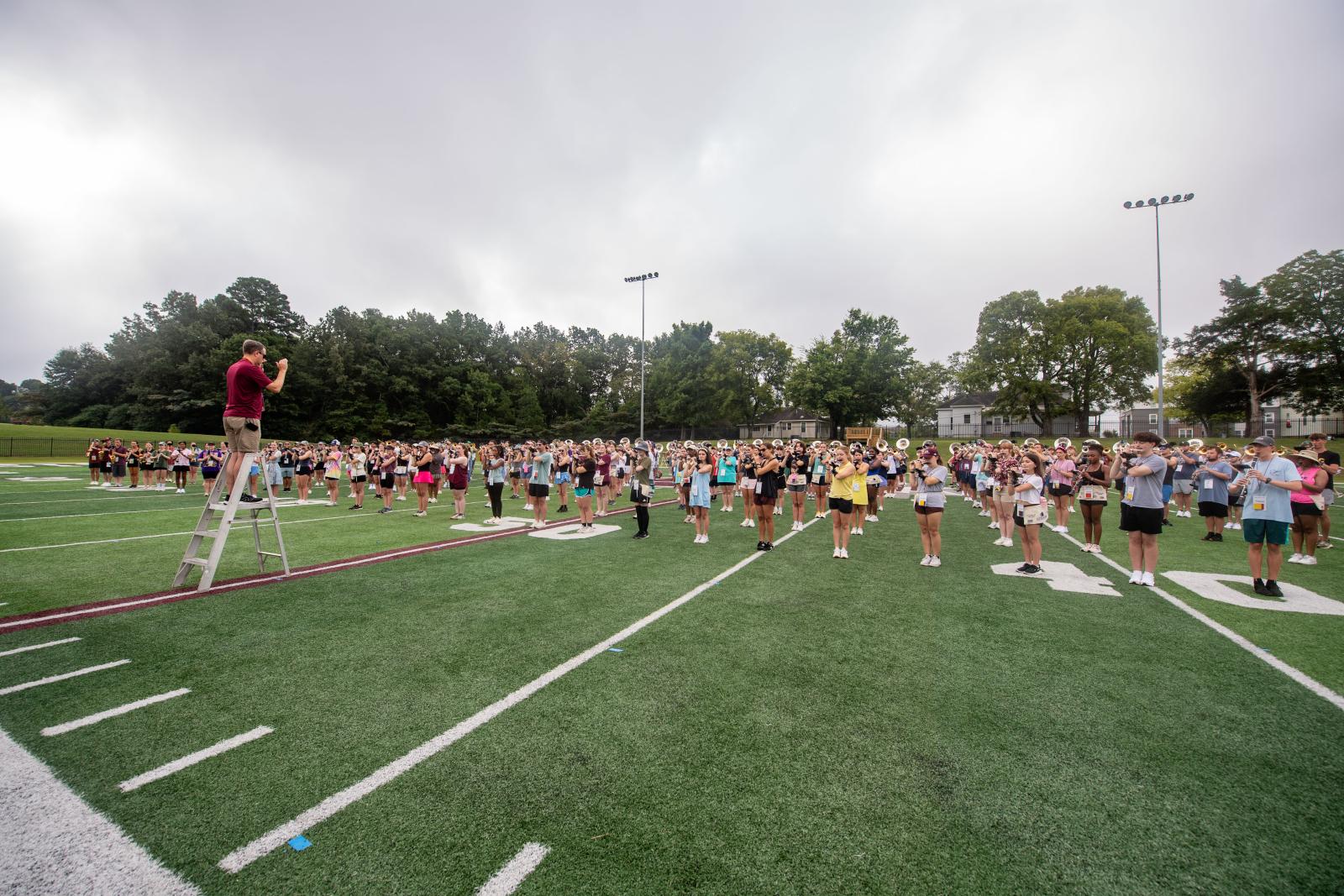 Students practice playing instruments on a band practice field