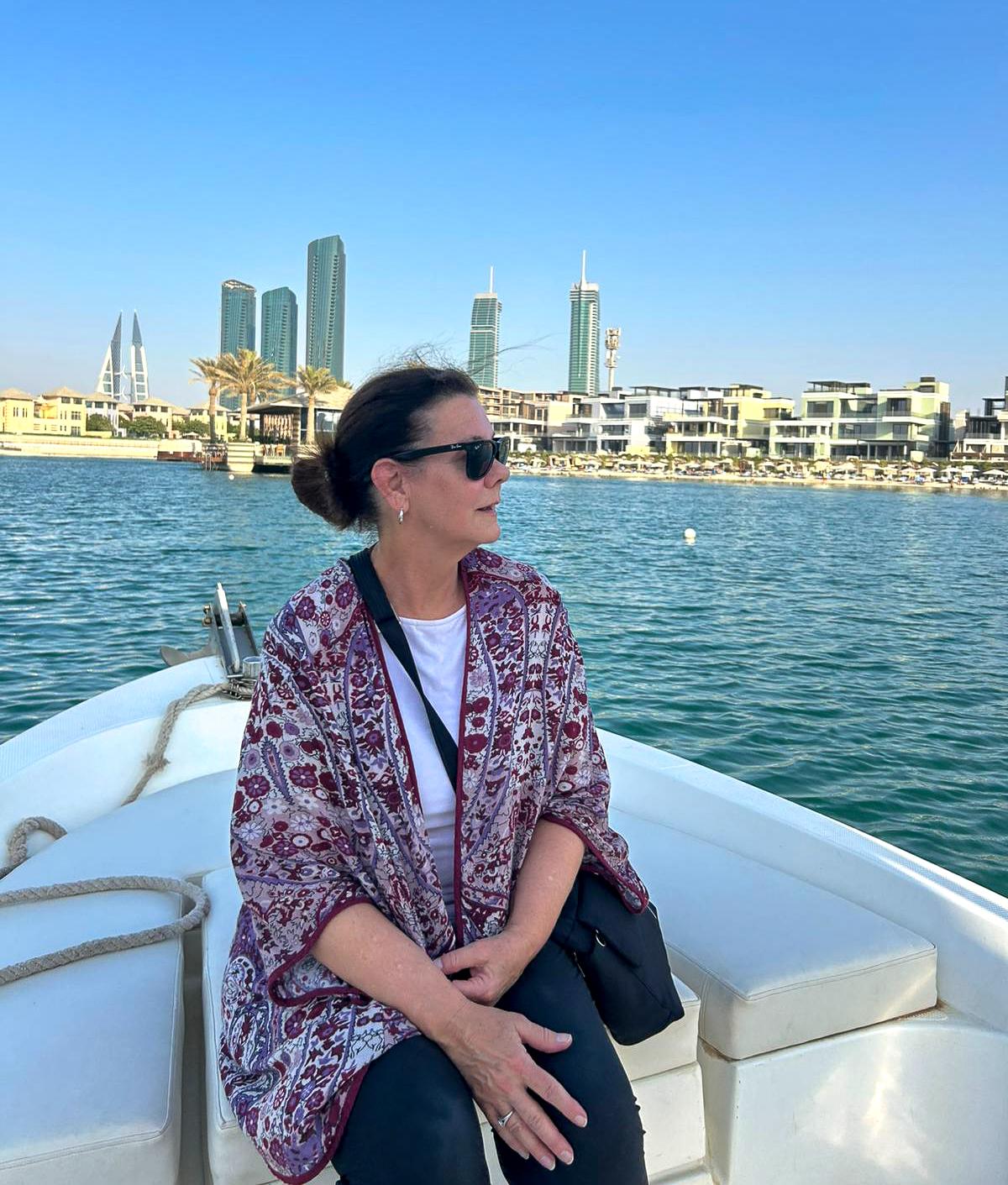 Missy Hopper rides on a boat with city behind her