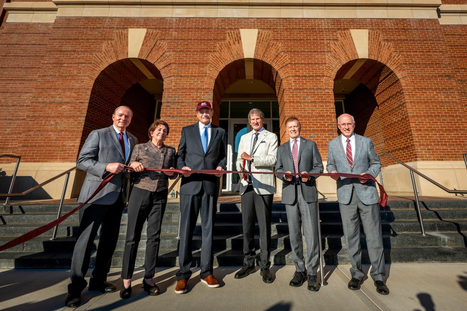 University leaders cut ribbon in front of building