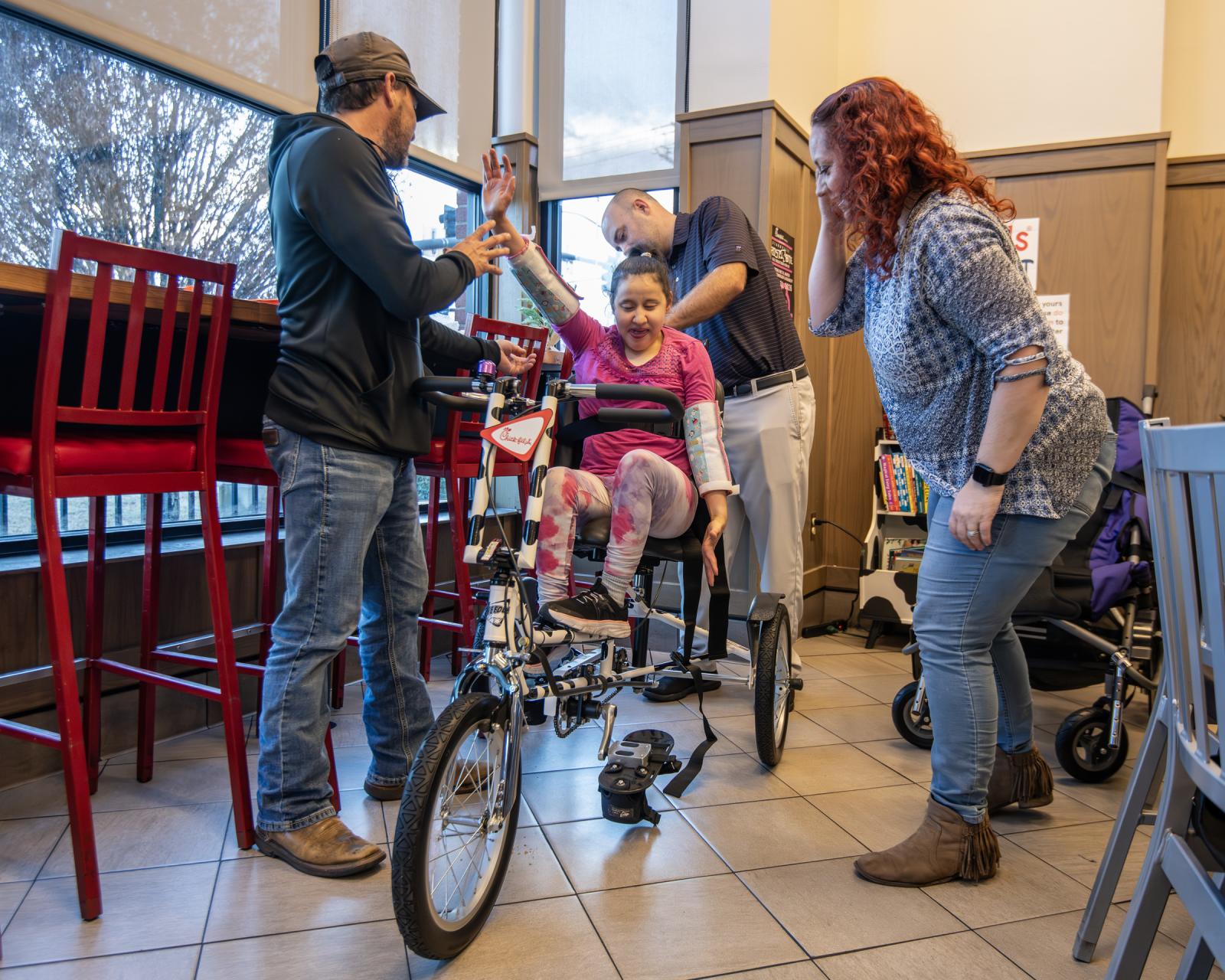 Child gets settled into new bike with assistance from parents