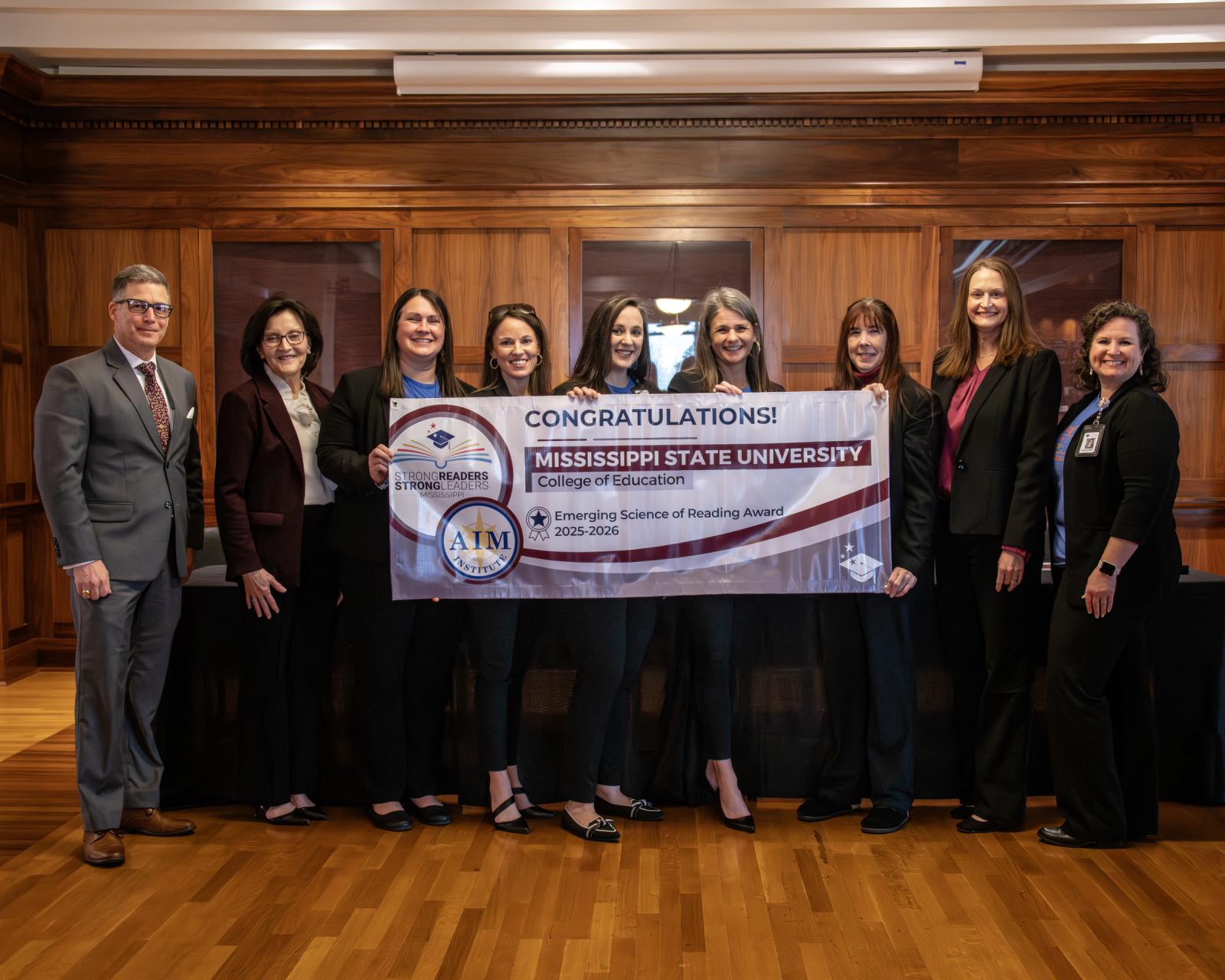 MSU and MDE leaders post together with a banner to celebrate Science of Reading designation