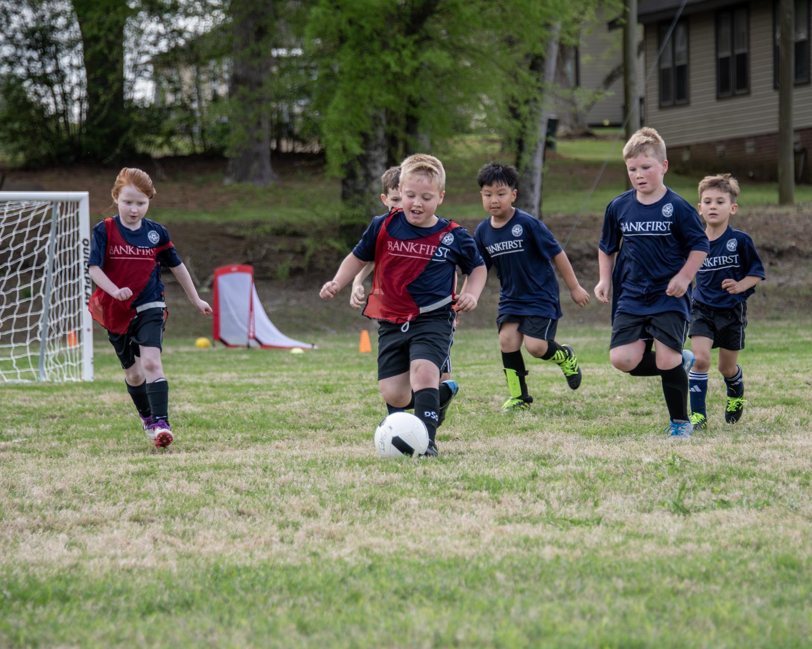 Children play soccer outside on a field