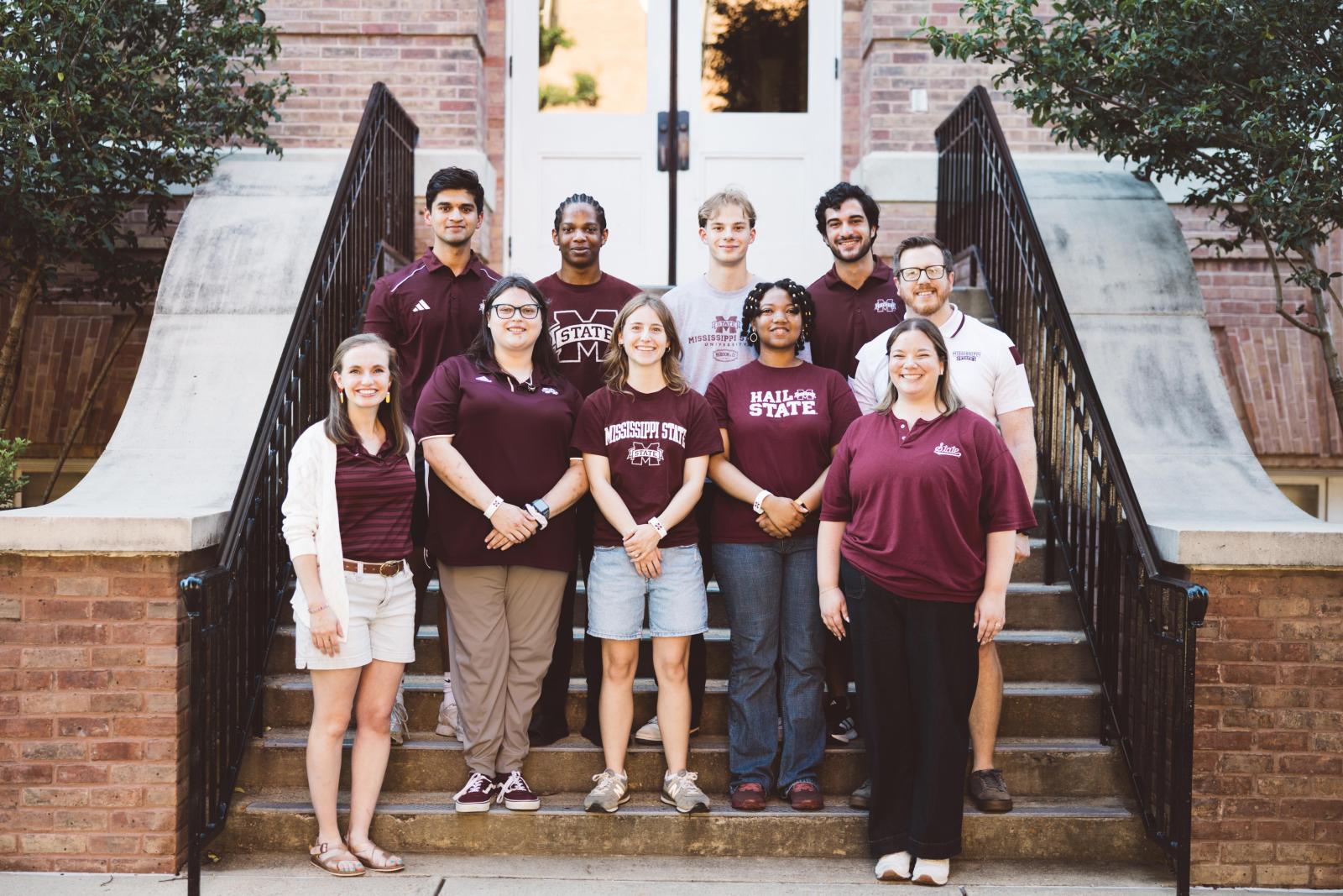 Photo of MSU alumni and students wearing maroon on the steps of a building outside
