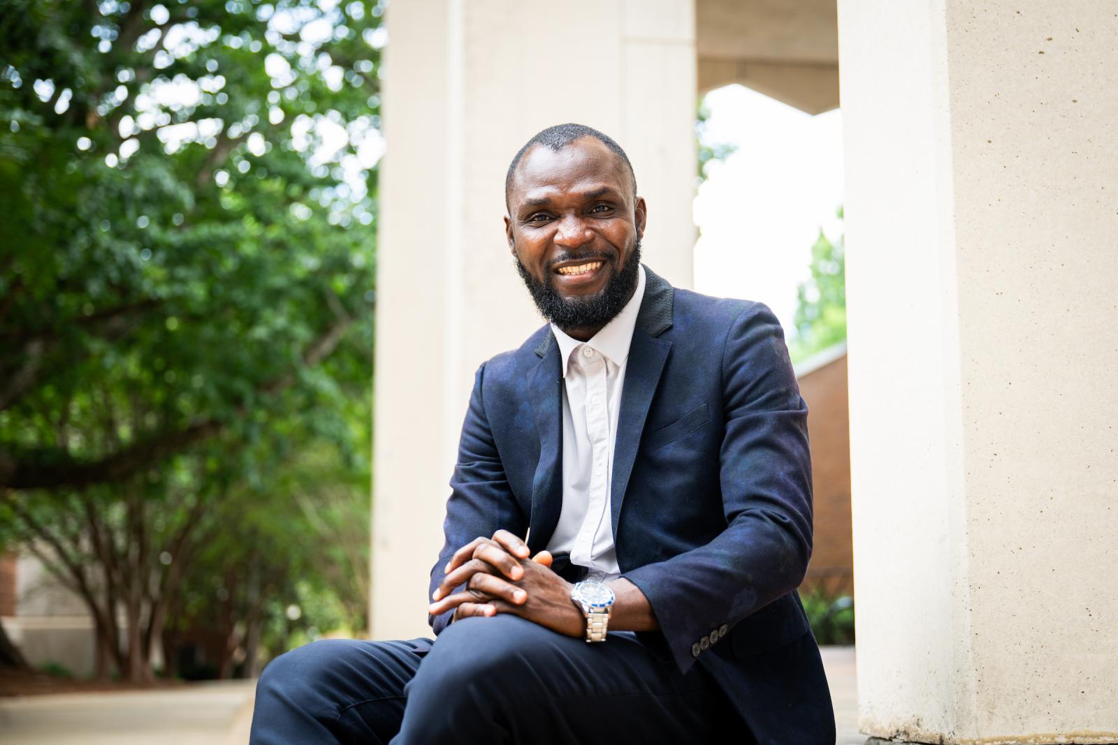 Timothy Okunoye sitting on steps of Allen Hall