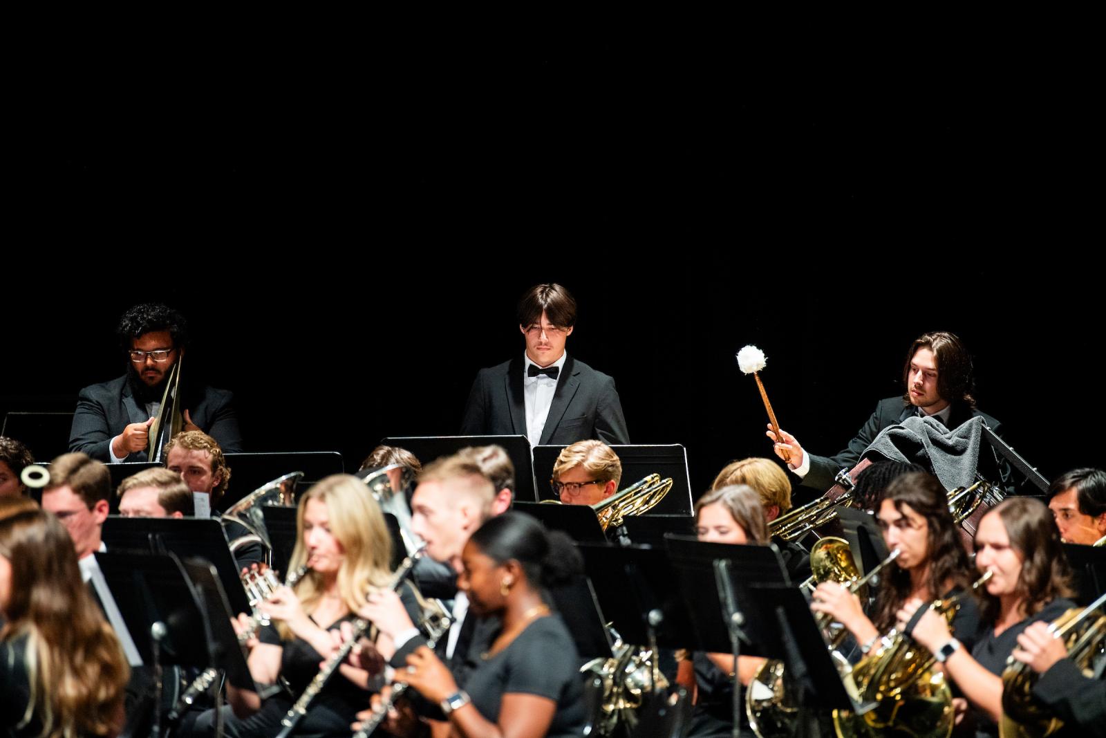 Student musicians play instruments in a concert.