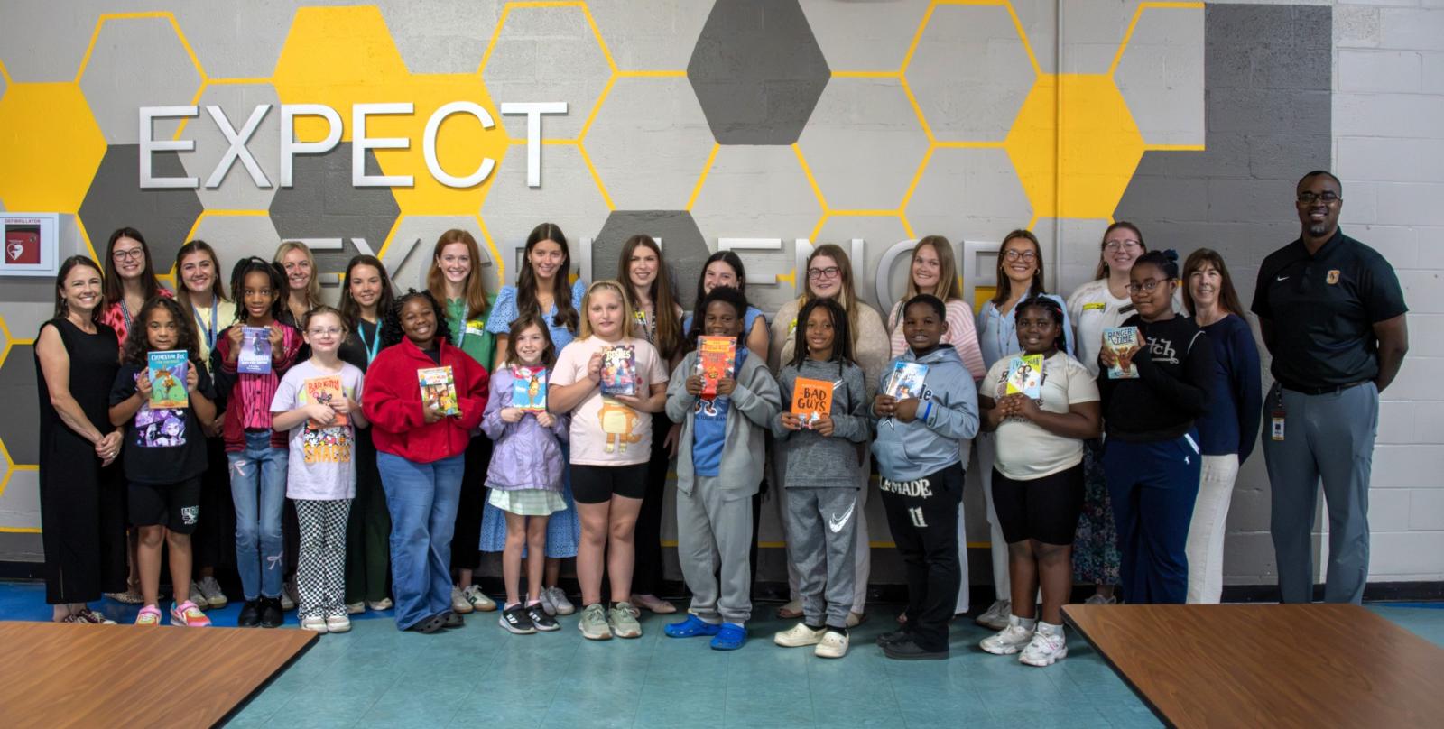 MSU students and children pose for a group photo with children holding books