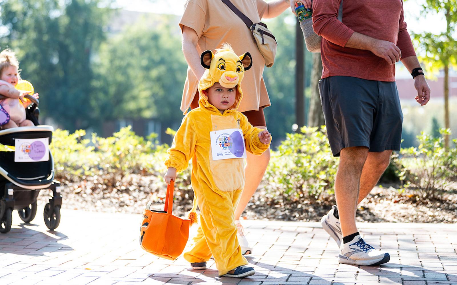 Child dressed in a costume walks on a sidewalk