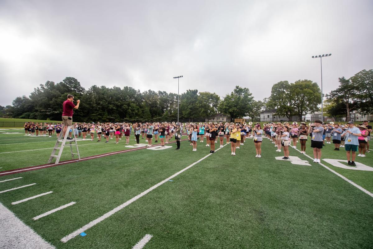 Students practice playing instruments on a band practice field