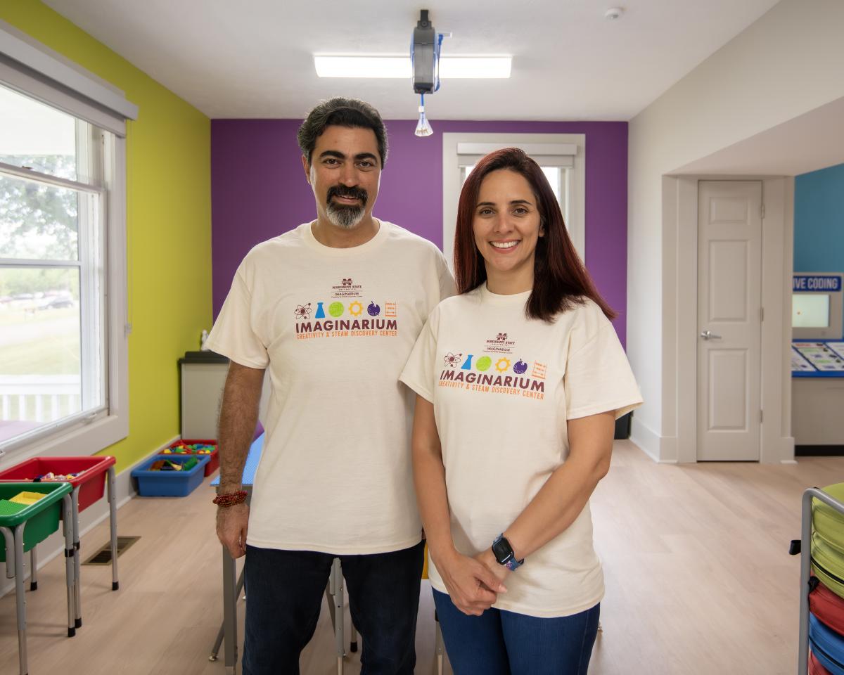 Two faculty members pose in Imaginarium for photo