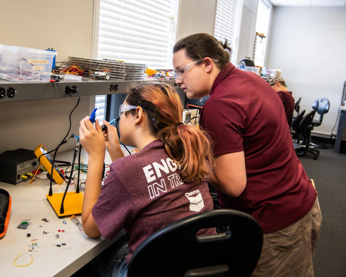 Instructor assists a student in a lab during a summer camp